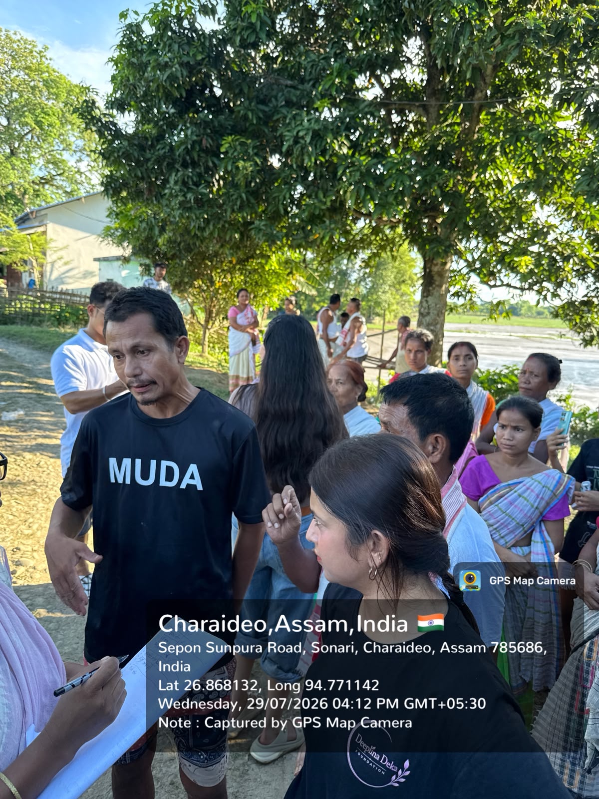 Field volunteers speaking with residents beside a flood-affected village road